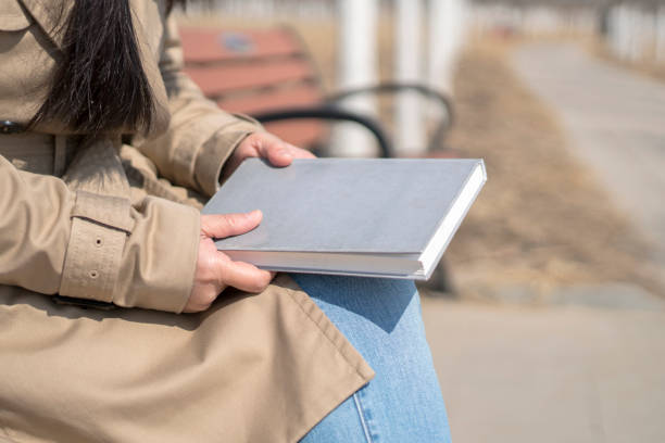 istock girl reading book in public park 943292478