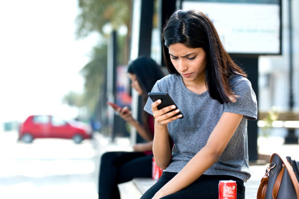 Woman holding drink can and texting on mobile phone