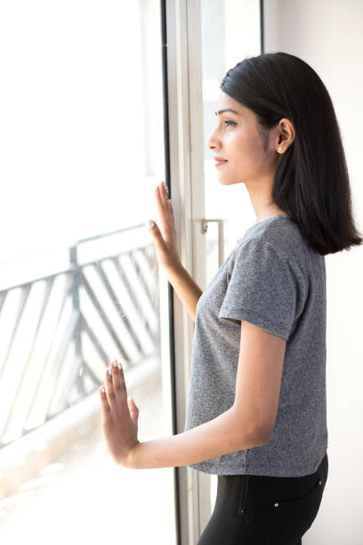 istock Woman looking out through window 943296252