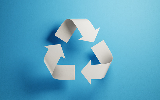 Recycling symbol made of paper on blue background. Horizontal composition with copy space. Green energy concept.
