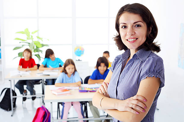 istock Female teacher standing on the foreground in a class room. 94330068