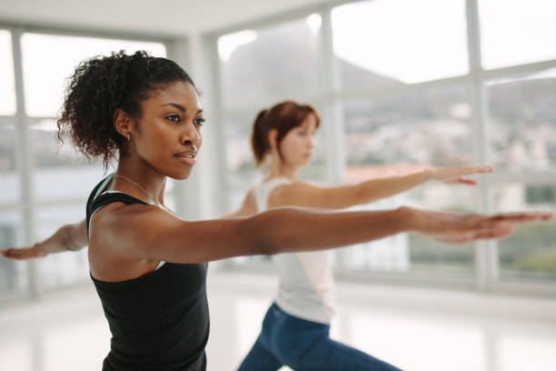women performing yoga in fitness studio - instructor exercising gym women imagens e fotografias de stock