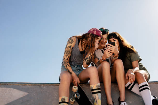 istock Female skaters sitting at skate park using smartphone 943304506