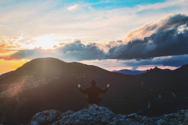 istock Young man in a lotus pose sits on the edge of the cliff 943304850