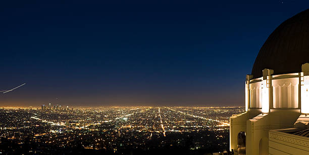 Griffith Observatory cityscape, LA Bright lights and streaking aircraft illuminating the Los Angeles basin to the far horizon from the art deco domes of the newly restored observatory and planetarium in Griffith Park overlooking the avenues and boulevards below. Adobe RGB 1998 color profile. griffith park photos stock pictures, royalty-free photos & images