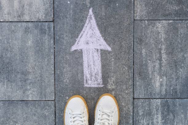 istock Feet and arrow on road. 943307792