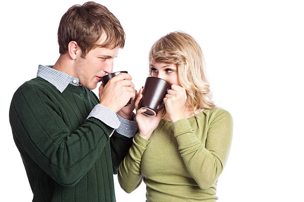 Midsection of unrecognizable young man embracing his loving girlfriend and they are both holding onto a hot cup of tea to warm their hands up while enjoying being outdoors on a cold winter day.