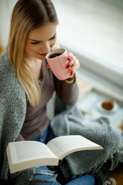 istock Young woman sitting on the floor and reading book 943315810