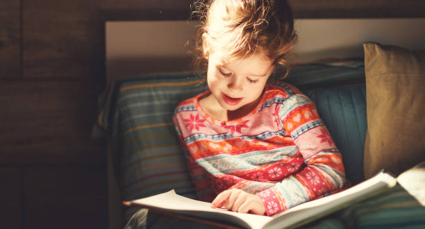 istock girl child reads book in bed 943322880