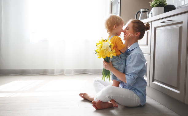 gelukkige moederdag! zoontje geeft flowersfor moeder op vakantie - keuken huis fotos stockfoto's en -beelden