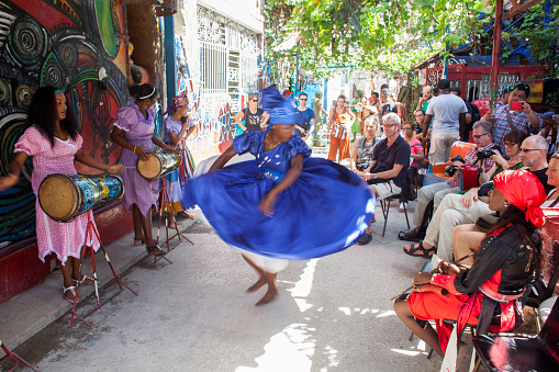 A dancer in a folk costume dances to the rhythm of traditional music surrounded by tourists in the Callejón de Hamel, one of the most visited places in Havana