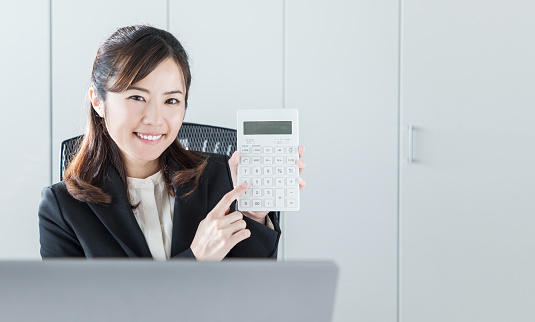 Young businesswoman showing a calculator.