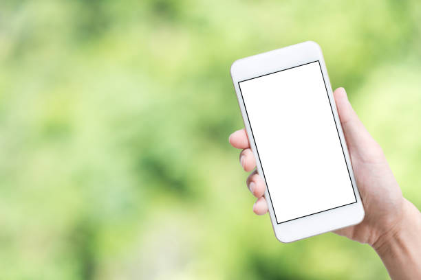 istock Hand holding smartphone with white mock-up screen over green abstract bokeh background. 943337876