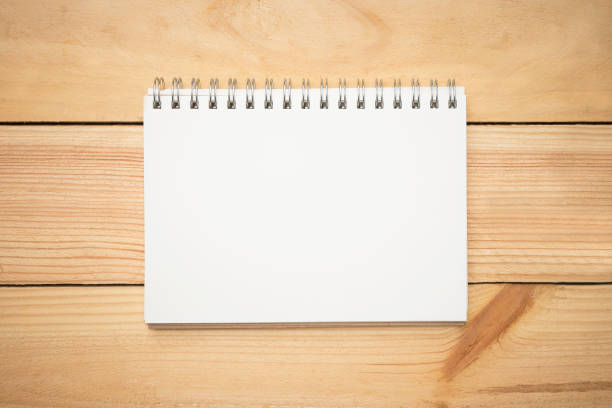 istock Blank notebook page in the middle of wood office desk table. Top view, flat lay. 943337904