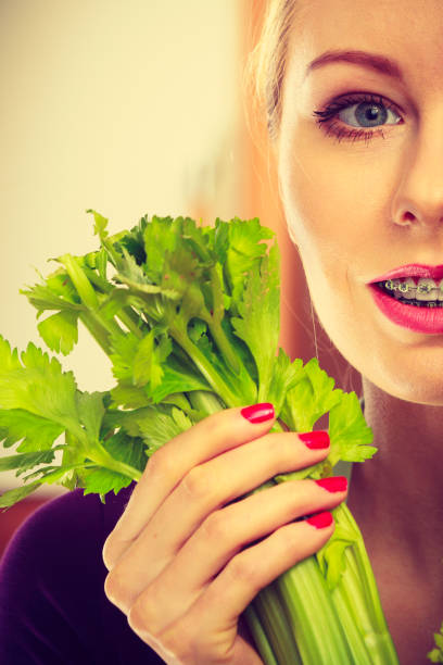 istock Woman in kitchen holds green celery 943347694