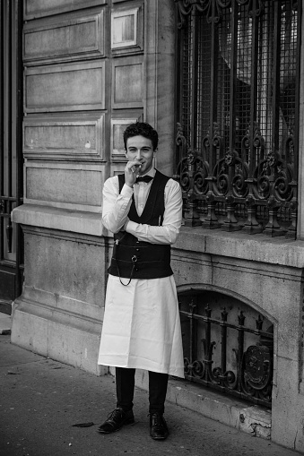 Waiter smoking a cigarette outside a restaurant located on Ile de la Cite, Paris.