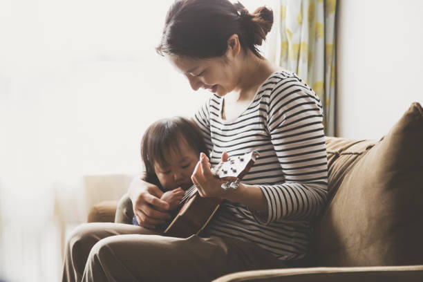 istock Mother and baby playing ukulele at home 943351882