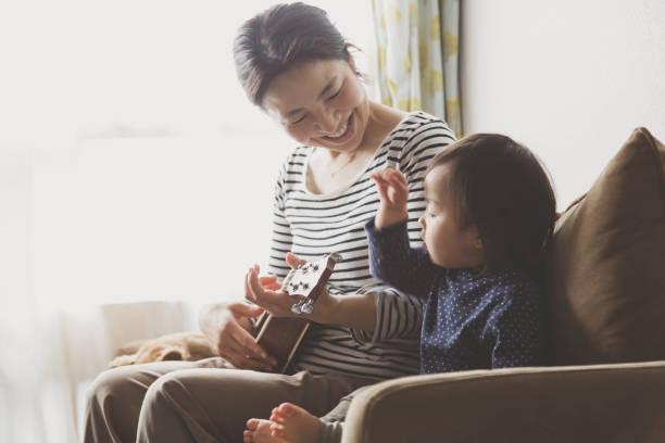 istock Mother and baby playing ukulele at home 943351888