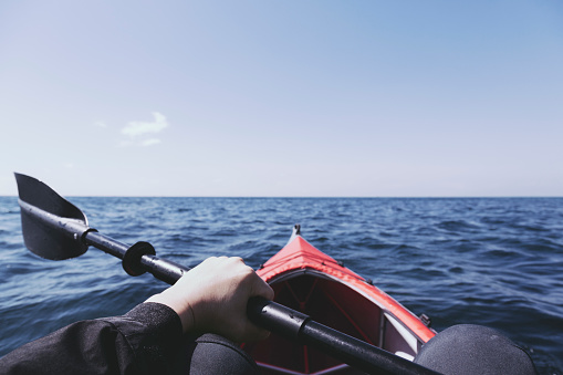 Hand of man holding an oar and handling kayak in the sea.
