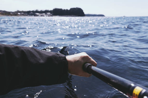 Hand of man holding an oar and handling kayak in the sea.