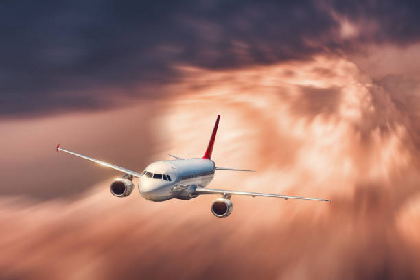 istock Big modern white airplane with motion blur effect is flying over low clouds at sunset. Passenger airplane, blurred clouds, sky, sunlight in dusk. Passenger aircraft. Business travel. Commercial plane 943355118