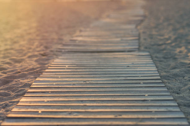 Wooden tootpath on the beach in the rays of the setting sun
