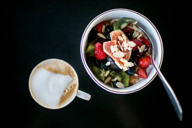 Frukost skål med bär och kaffe Havregrynsgröt med bär och frukt och skummad kaffe bär stock pictures, royalty-free photos & images