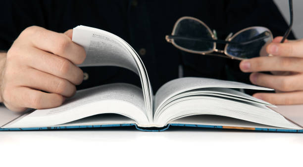 istock Man's hands and man looking for something in the book closeup 943386970