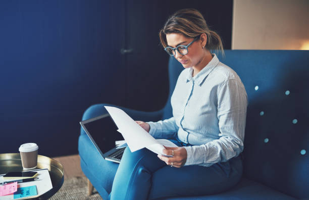 istock Young businesswoman reading paperwork while sitting on a sofa 943388942