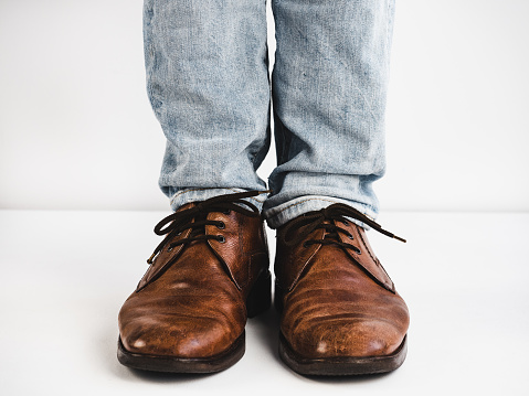Vintage, brown shoes, jeans and man's feet on a white background. Fashion, style, beauty