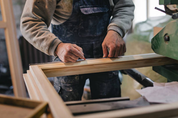 Carpenter Measuring a Wooden Plank Mature carpenter measuring window frame in the workshop wood windows stock pictures, royalty-free photos & images