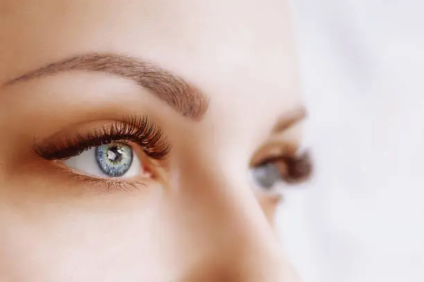 Photo of Eyelash Extension Procedure. Woman Eye with Long Eyelashes. Close up, selective focus