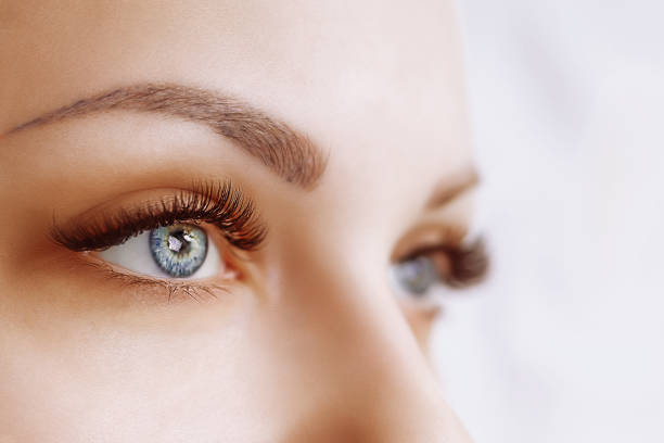 eyelash extension procedure. woman eye with long eyelashes. close up, selective focus - human eye eyebrow eyelash beauty imagens e fotografias de stock
