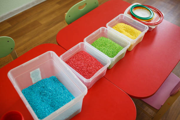 istock Sensory bin for toddlers with colourful rice on red table 943401292