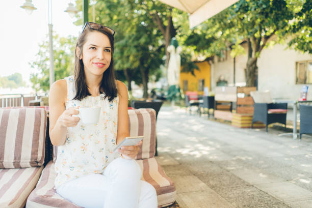 istock Girl using her smartphone and drink coffee outdoor 943411574