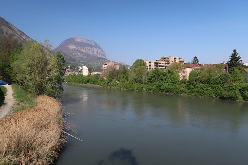 Grenoble, France – April 07, 2017: photography showing the Isère river as well as the Dent de Crolles (Chartreuse mountain famous geological formation) in the background. The photography was taken from the street of the city of Grenoble.