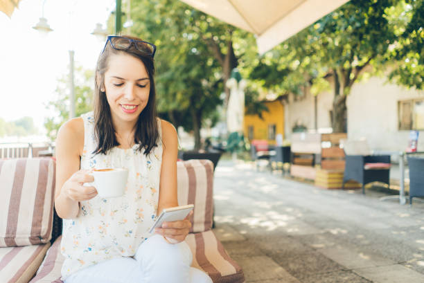 istock Girl using smartphone and drink coffee outdoor 943411678