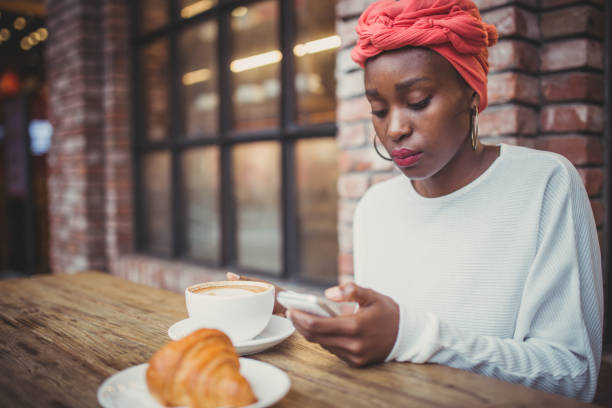 istock Young woman texting while sitting in coffee shop 943414264