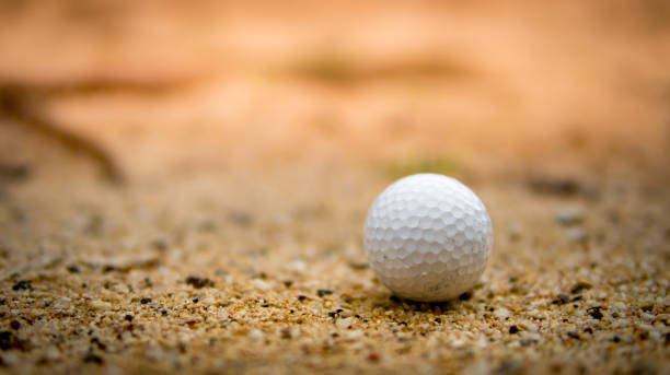istock Golf ball on sand bunker on sunset 943414754