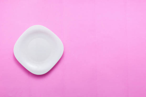 istock Single empty plate on pastel pink background top view flat lay copy space 943418336