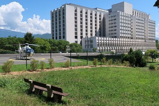 La Tronche, France – June 02, 2017: photography showing Grenoble teaching hospital and a rescue helicopter stationed on the heliport of the north hospital of the city of Grenoble. The photography was taken from the city of La Tronche near Grenoble, France.