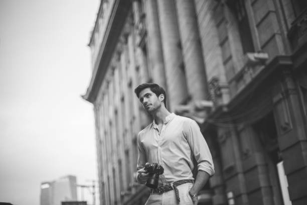 Man photographer holding digital camera and taking photos outdoors
