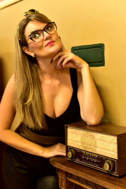 Blonde woman with a vintage look listening to an old radio