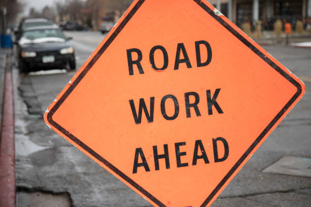 istock Road work ahead sign with parked cars 943465716