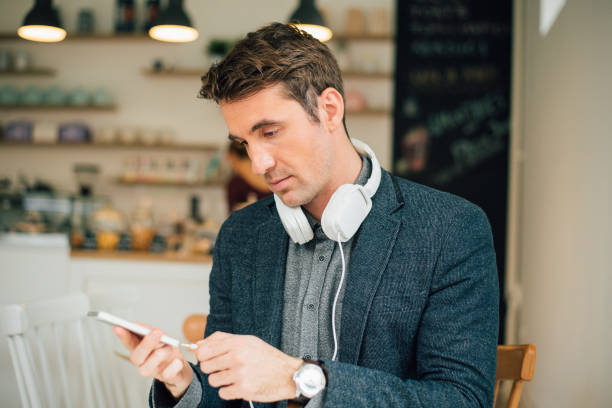 istock Man putting headphones in mobile phone 943471932