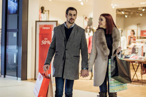 istock Couple in love holding hands while exiting shopping mall 943476132