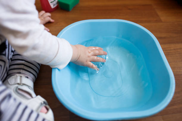 istock Toddlers hands in a blue basin on the floor 943478948