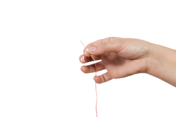 istock people, stitching, embroidery, needlework and sewing concept - hands of tailor woman threading needle 943483950