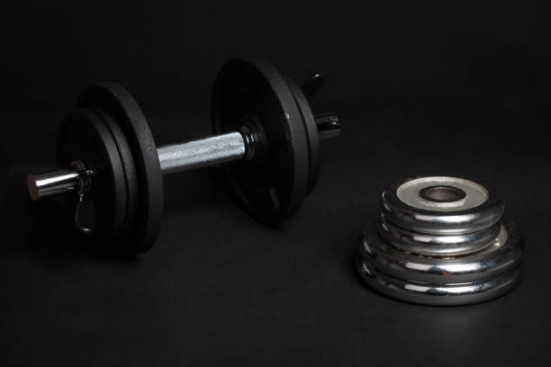 istock Dumbbell and barbell discs for workout on black background 943489308