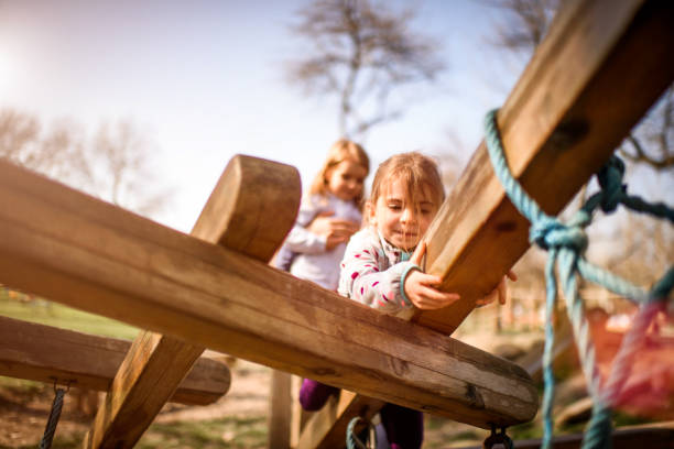 Little girls playing in the park on wooden planks.